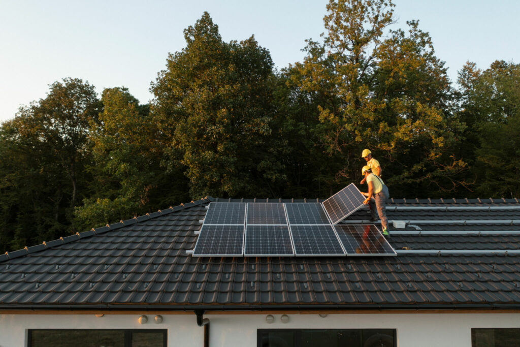 Two Professionalists Installing Solar Panels On A Roof Of A Modern House.